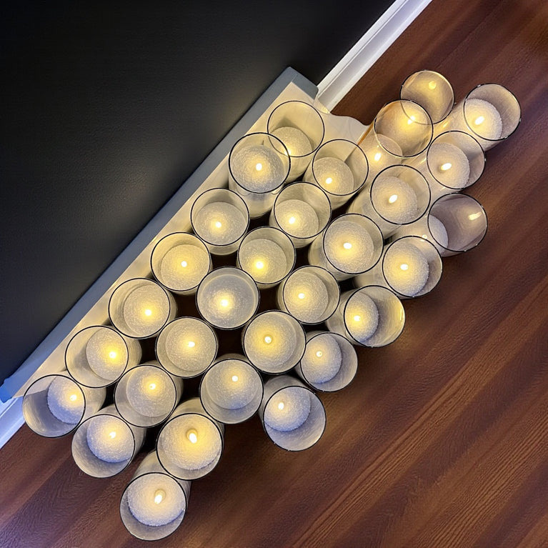 Decorative wall art made of lit candles arranged in a geometric pattern on a wooden surface.