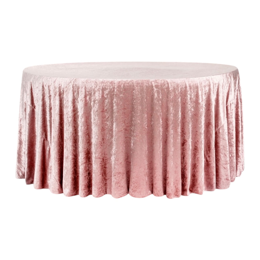 Round table covered with a dusty pink velvet tablecloth on a white background