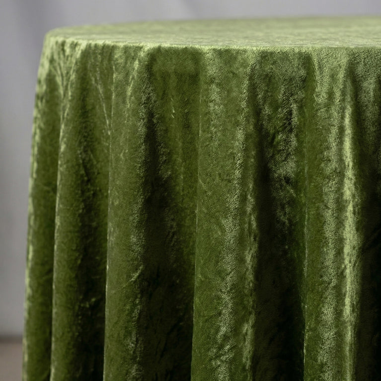 Sage green velvet tablecloth on a round table with a neutral background