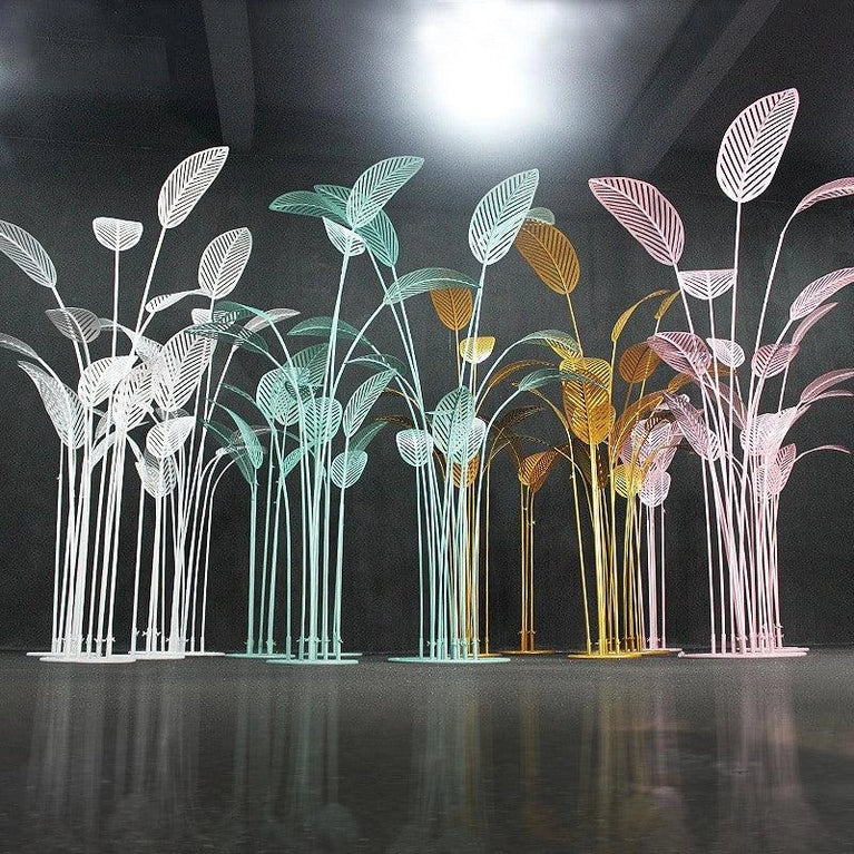 Decorative metal palm tree sculptures in various colors on a reflective surface.