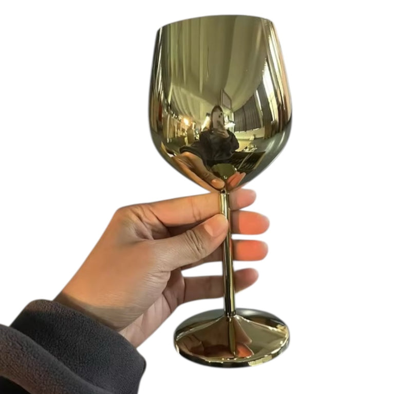 Gold wine glass held by a hand against a white background