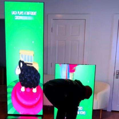 Person interacting with a large led screen displaying colorful graphics in a room.