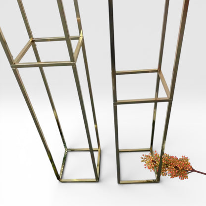 Two metallic square shelves on a white background with a small plant.