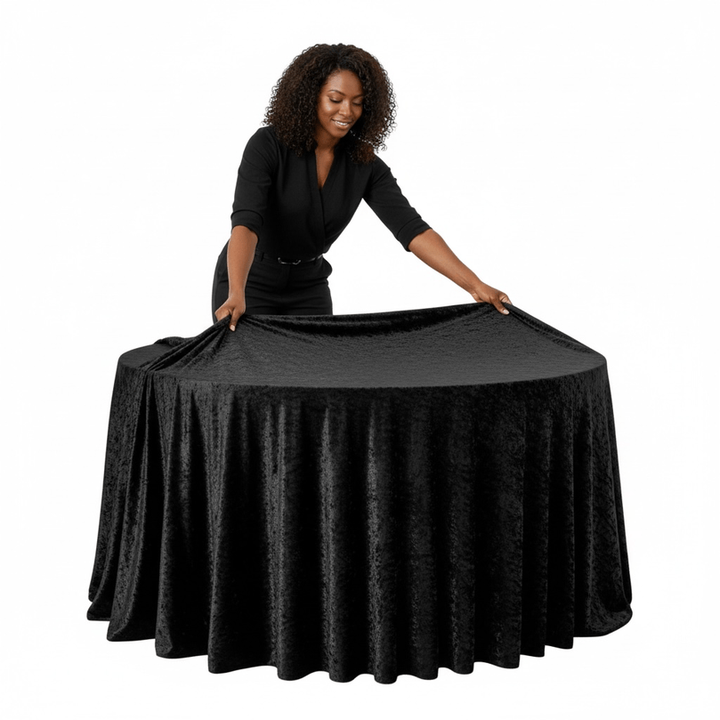Woman arranging a black velvet tablecloth on a round table against a white background