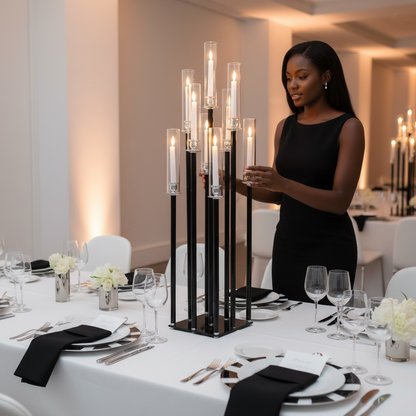 Woman arranging candles into a large black candle holder on a table in a formal dining setting