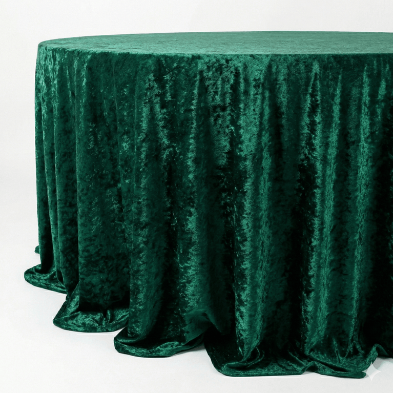 Emerald green velvet textured tablecloth on a round table against a white background
