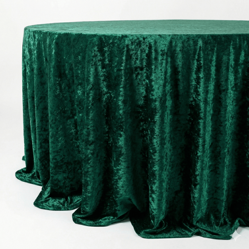 Emerald green velvet textured tablecloth on a round table against a white background