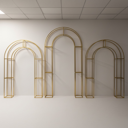 Set of gold arch-shaped wedding backdrops against a white wall.