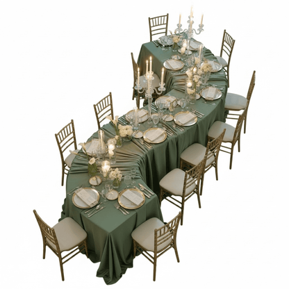 Elegant dining table set with green tablecloth, white plates, and silverware on a white background