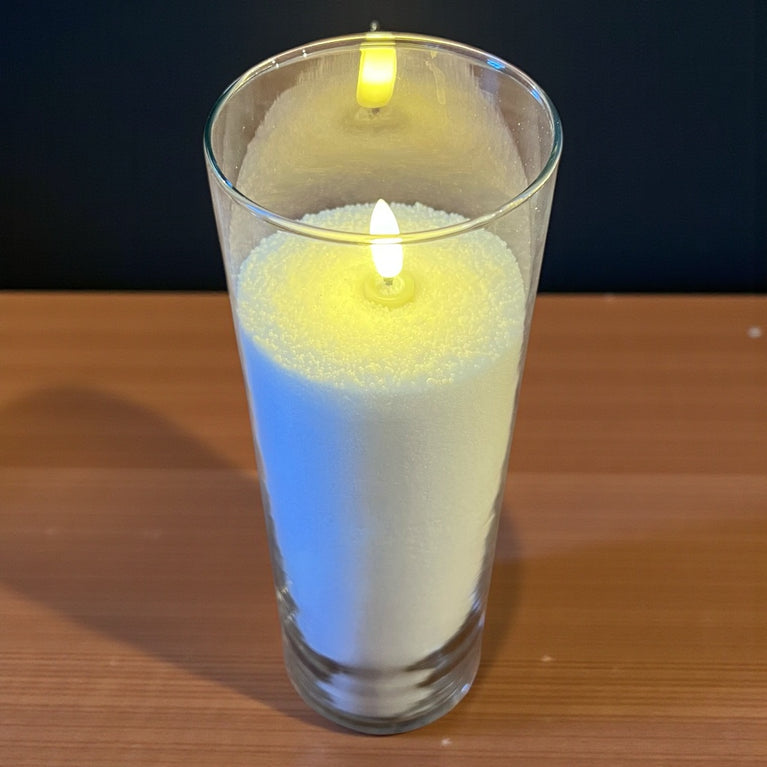 Candle in a glass container on a wooden surface with a dark background