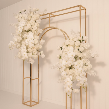 Decorative floral arch with white flowers and gold metal frames on a plain background