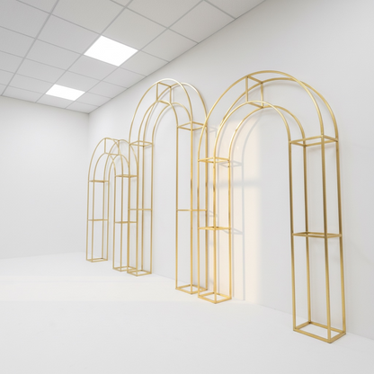 Set of gold arch-shaped wedding backdrops against a white wall.