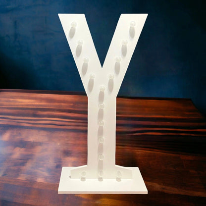 marquee light up letter Y with its lights off standing on a wooden floor