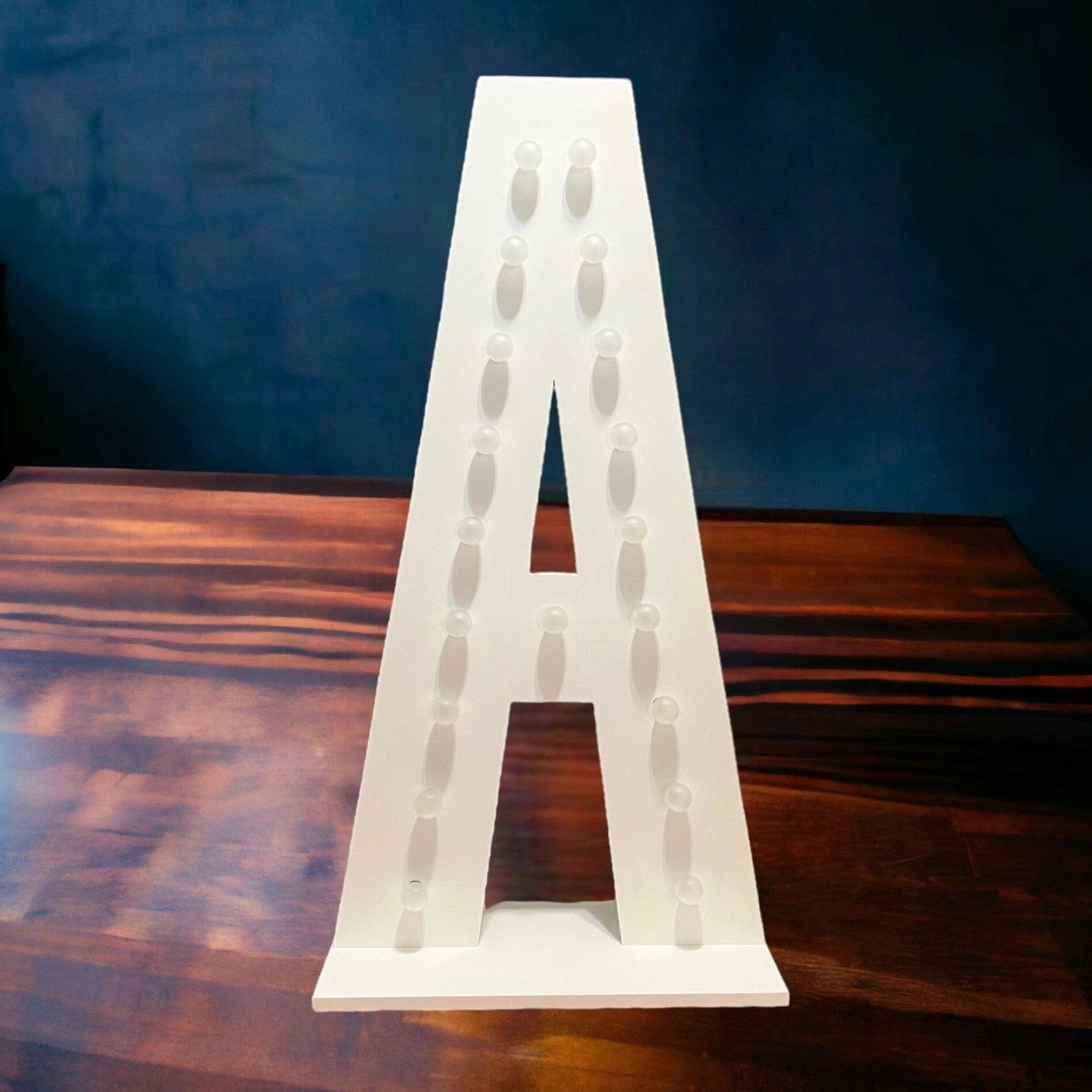 marquee light up letter A with its lights off on a wooden floor