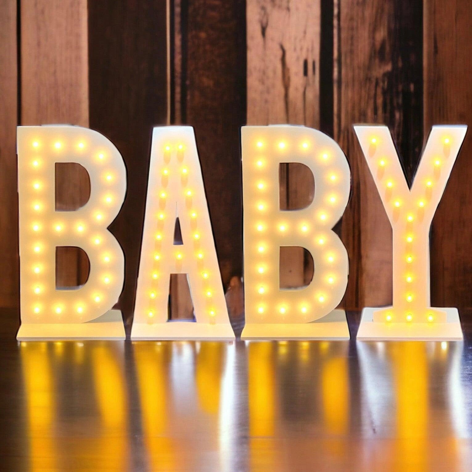 Light-up letters spelling 'BABY' on a wooden background