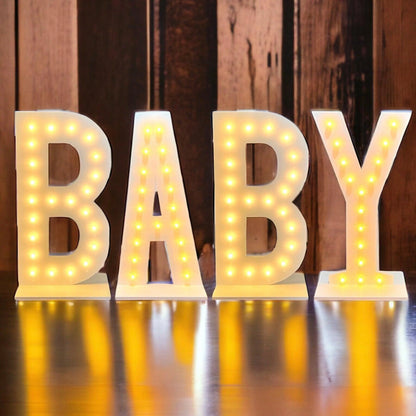 Light-up letters spelling 'BABY' on a wooden background