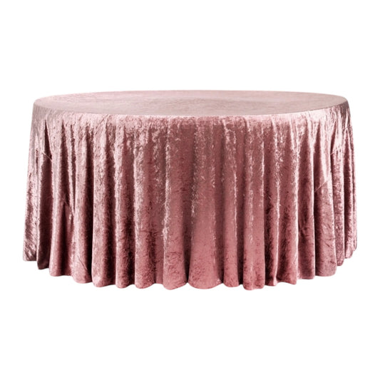 Round table covered with a pink velvet textured tablecloth on a white background