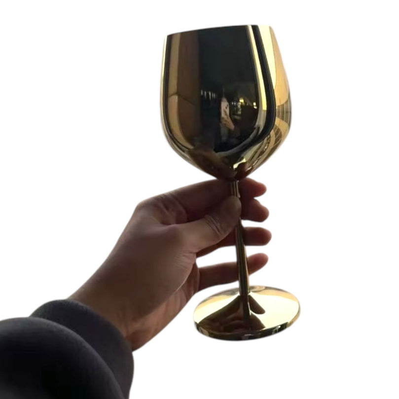 Gold wine glass held by a hand against a white background