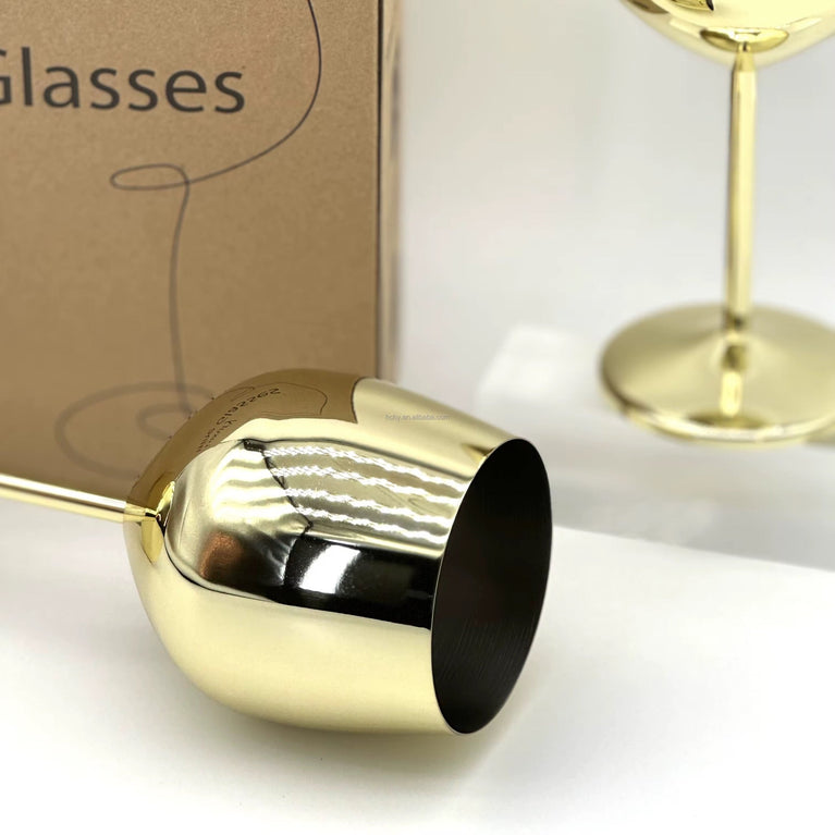 Gold wine glass on a white surface with a cardboard box labeled 'Glasses' in the background.