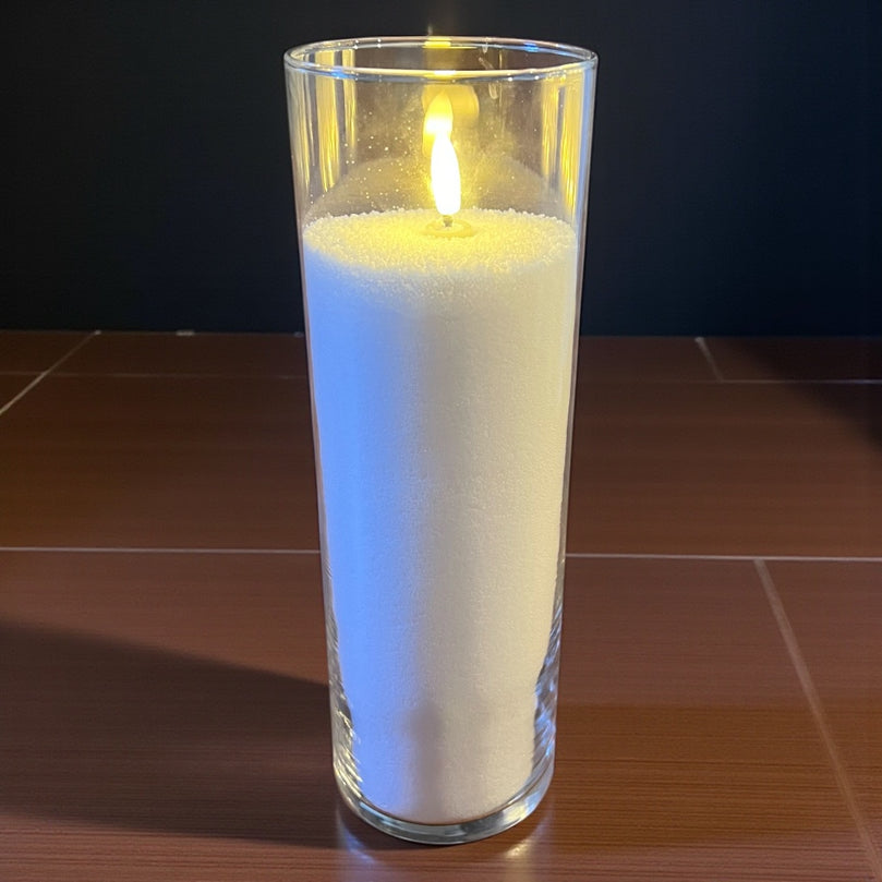 Candle in a glass container on a tiled surface with a dark background