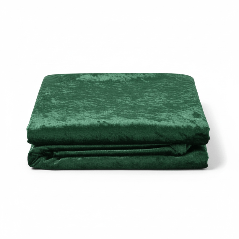 Folded emerald green velvet fabric on a white background