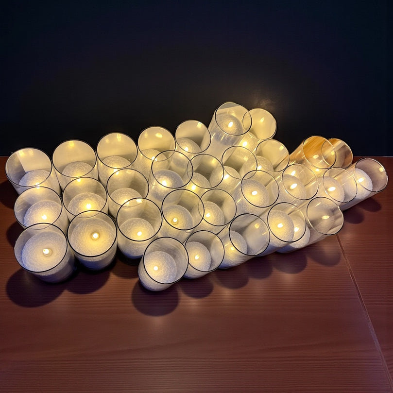 Multiple large, lit candles on a wooden surface with a dark background