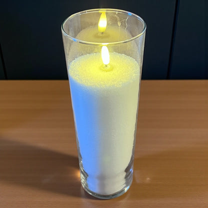 Candle in a glass container on a wooden surface with a dark background