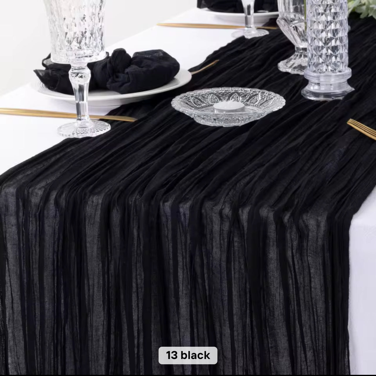 Black cheesecloth table runner on a white table with decorative items.