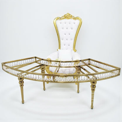 Decorative throne chair with gold frame and white cushion on a white background standing behind a crystal table