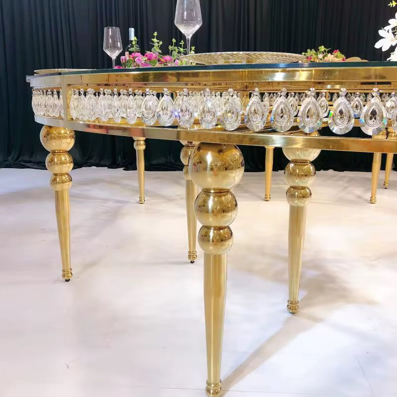 Gold dining table with crystal beads and wine glasses on a white floor