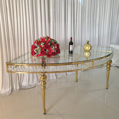 Gold and glass table with a bouquet of red flowers and a bottle of wine on a white curtain background