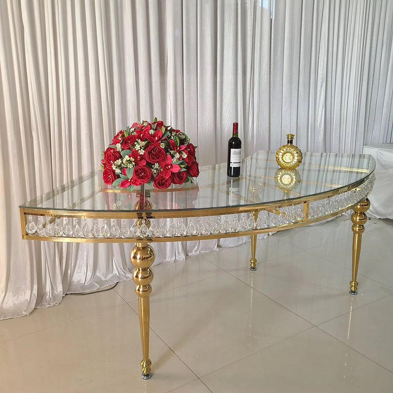 Gold and glass table with a bouquet of red flowers and a bottle of wine on a white curtain background