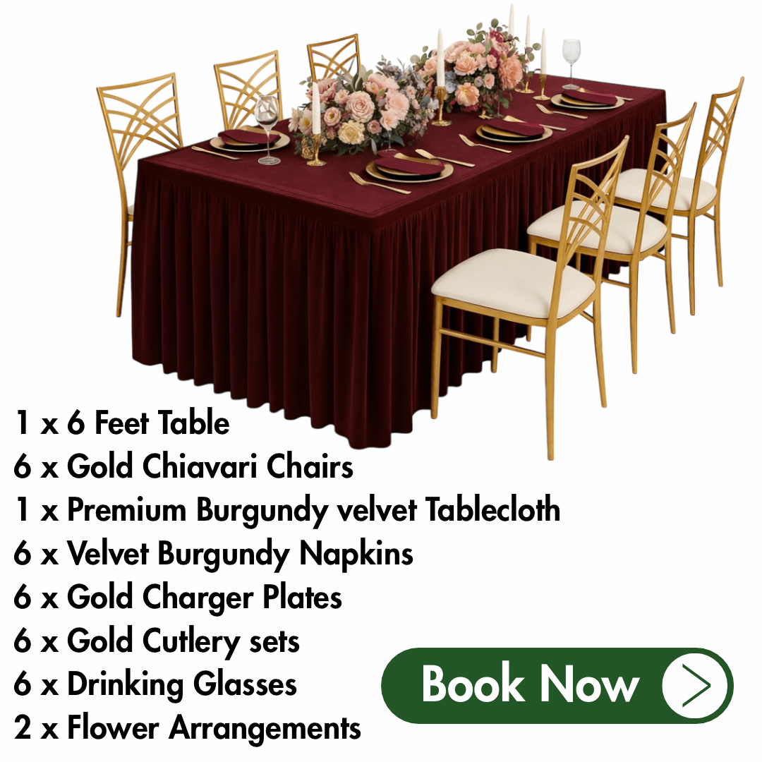 Table setting with burgundy velvet tablecloth, gold chairs, and floral arrangements on a white background.