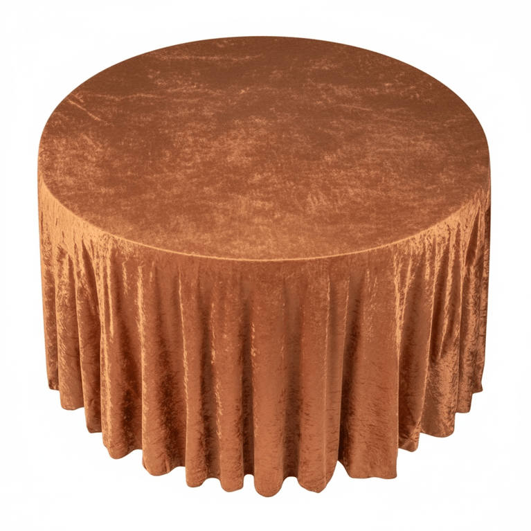 Round table covered with a rustic terracotta velvet tablecloth on a white background
