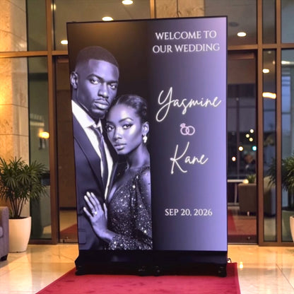 LED Wedding welcome sign with a couple's photo and event details in a formal setting.