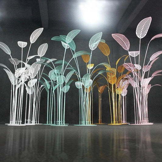 Decorative metal palm tree sculptures in various colors on a reflective surface.