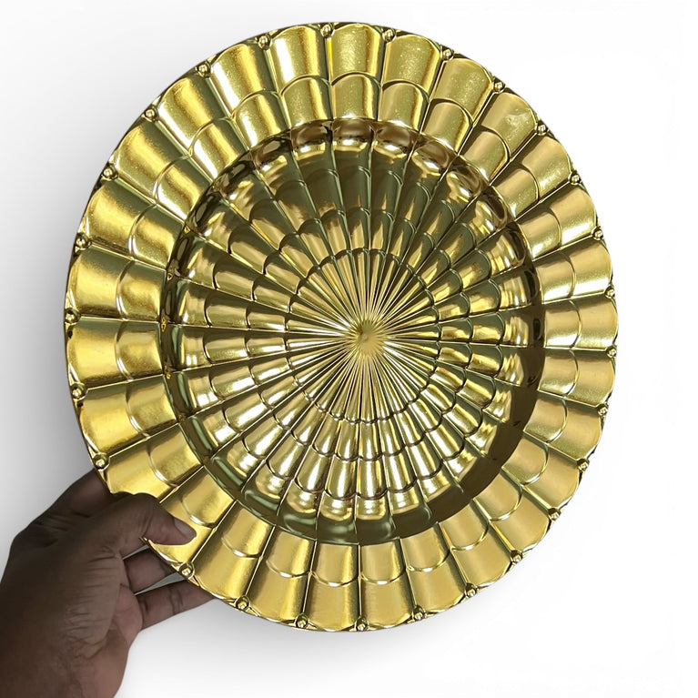Gold decorative charger plate held by a hand on a white background
