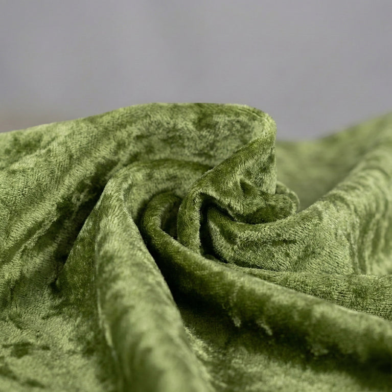 Close-up of sage green velvet tablecloth fabric with a textured surface on a gray background