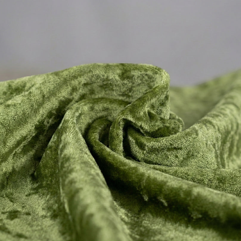 Close-up of sage green velvet tablecloth fabric with a textured surface on a gray background