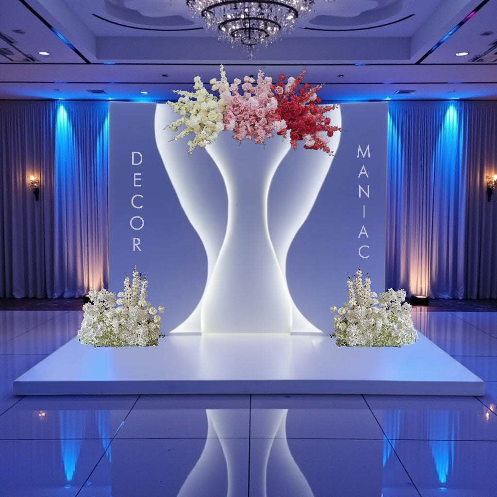 Decorative setup with large white backdrop holding flowers on a stage, with 'Decor Maniacs' branding.