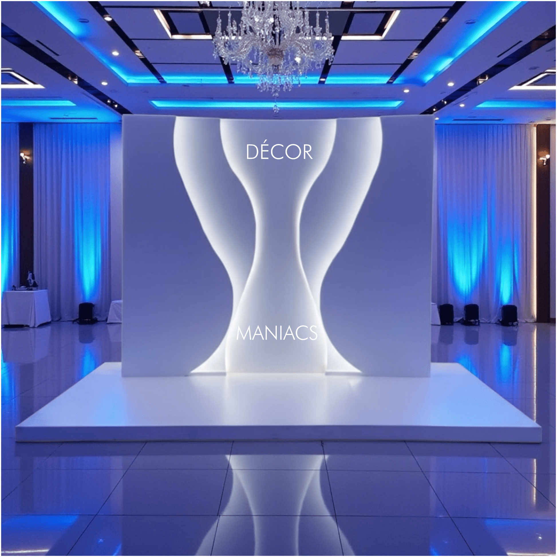 Decorative setup with a white backdrop arch and 'Décor Maniacs' branding in a room with blue lighting.