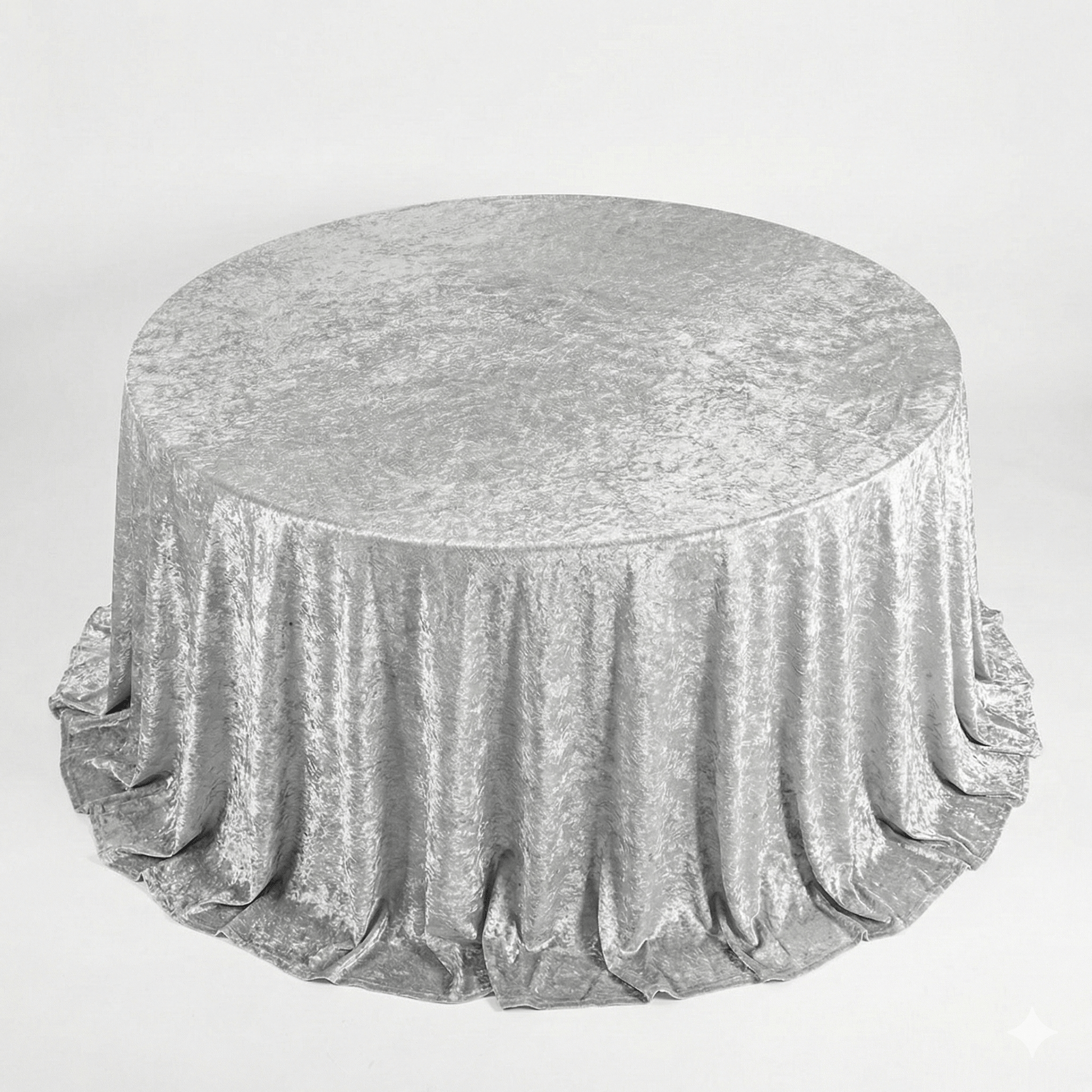 Round table covered with a silver velvet tablecloth on a light gray background