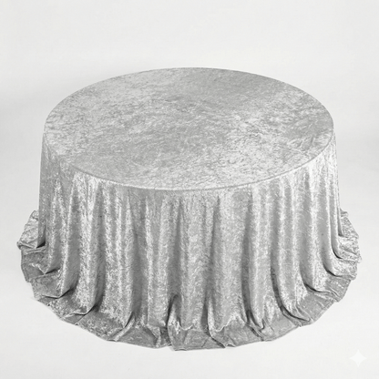 Round table covered with a silver velvet tablecloth on a light gray background