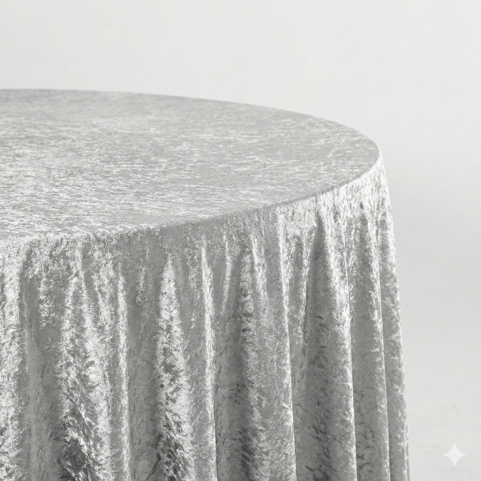 Round table covered with a silver crused velvet tablecloth on a plain background