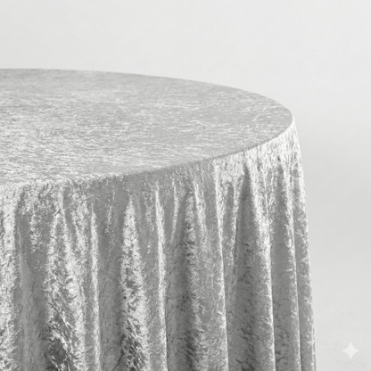 Round table covered with a silver crused velvet tablecloth on a plain background