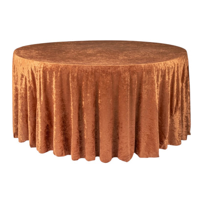 Round table covered with a rustic terracotta velvet tablecloth on a white background