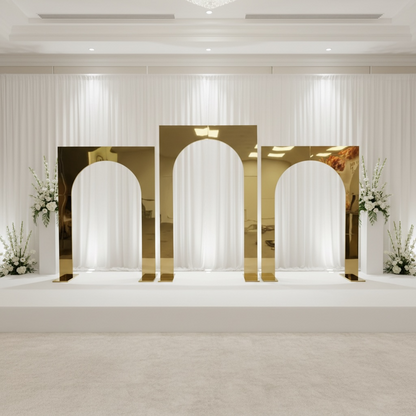Decorative wedding arches with gold frames and white drapes in a room setting.