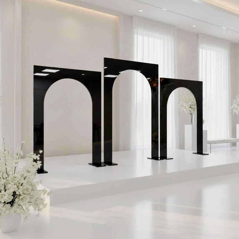 Modern wedding backdrops with black arch-shaped structures and white flowers.