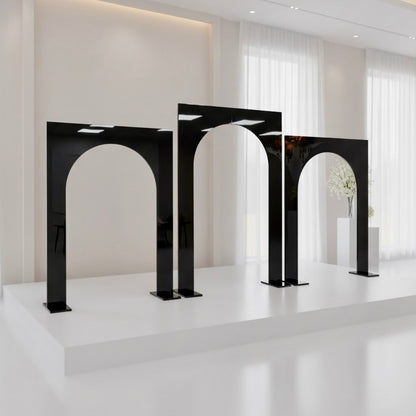 Modern black arch-shaped wedding backdrop stands in a white room