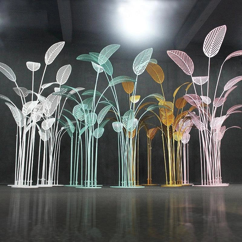 Decorative metal palm tree sculptures in various colors on a reflective surface.